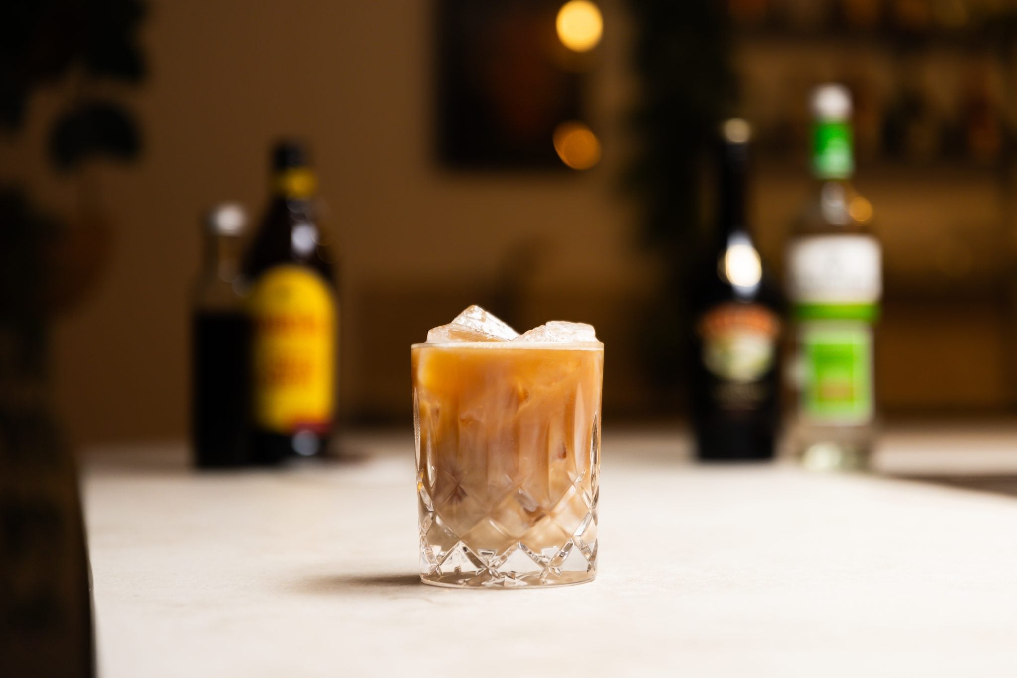 Vodka, coffee liqueur, irish cream, espresso, and cold brew coffee laid out on a white bar table