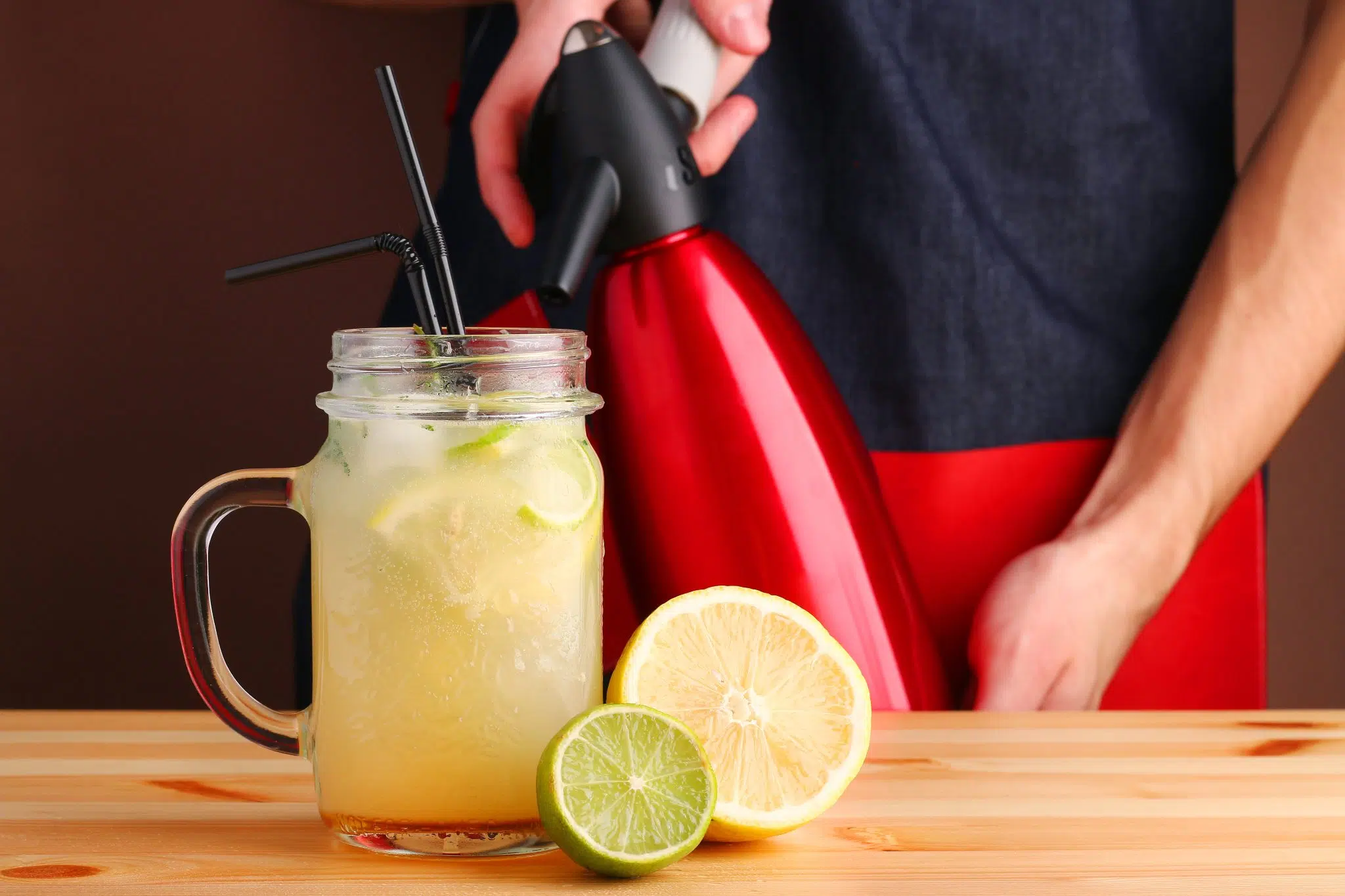 A shot of a red siphon pouring soda in a glass