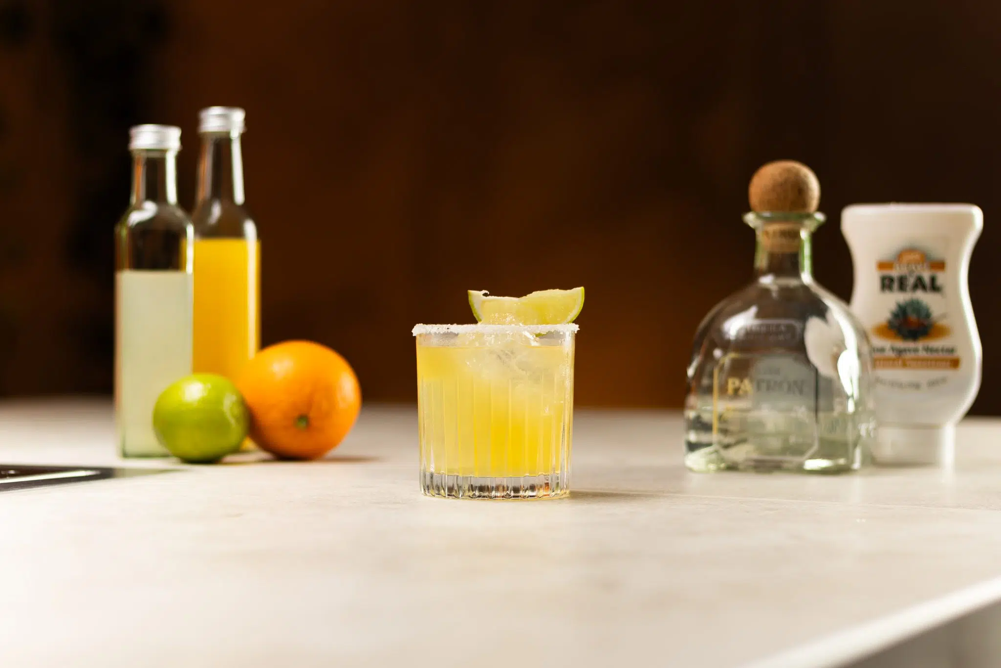 Lime juice, orange juice, Tequila, agave nectar, an orange and a lime laid out on a white bar table