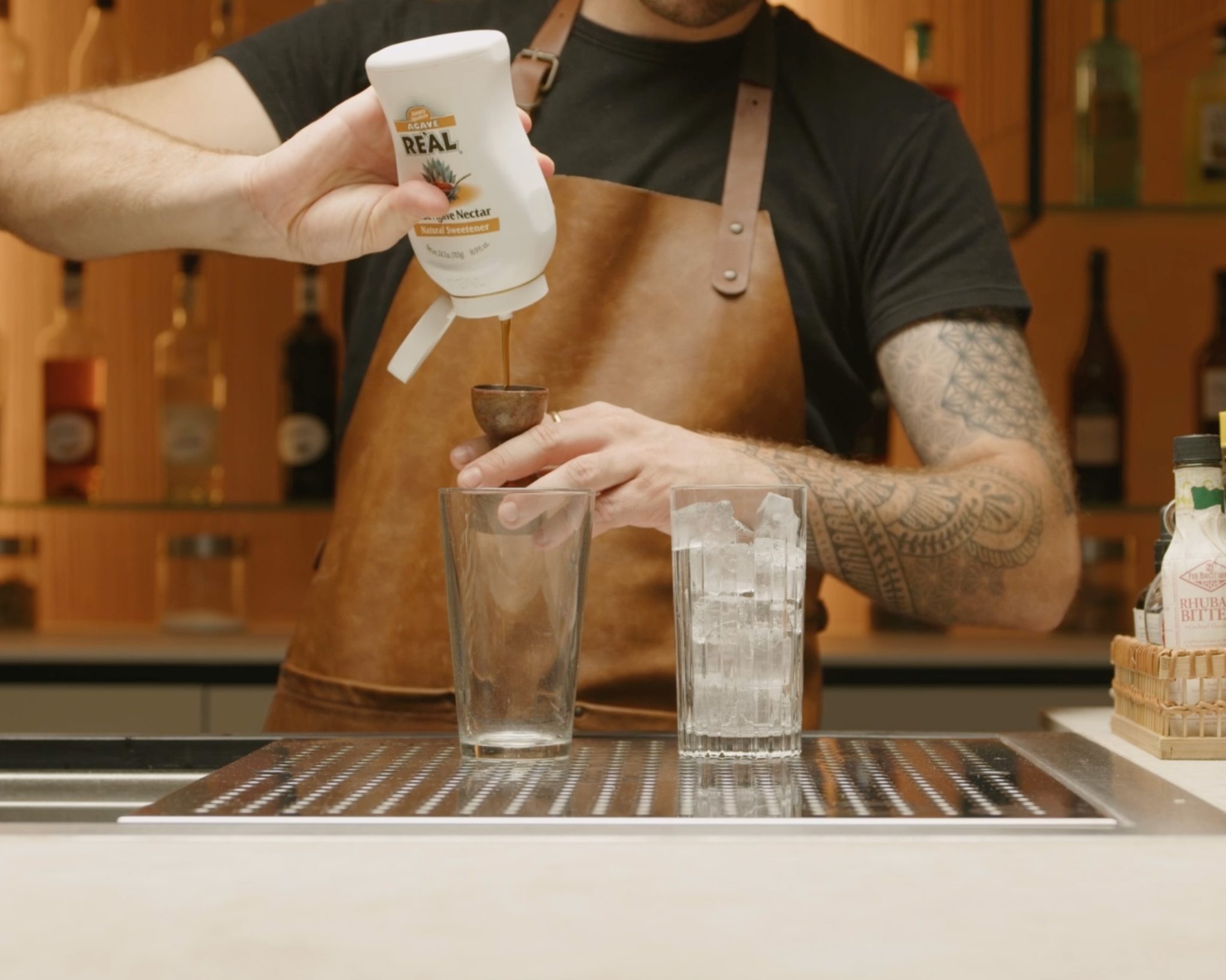 <p>In the shaker, pour in ½ ounce of agave syrup. This will impart a subtle sweetness that balances the tartness of the lime and pineapple juices, adding depth to the cocktail's flavor profile.</p>
