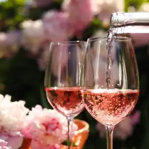 Two rosé sparkling wine glasses with a flowery garden on the background.