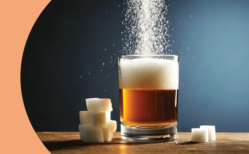 A shot of sugar poured into a low ball glass with beer on a brown surface surrounded by six sugar cubes, in front of a blue background