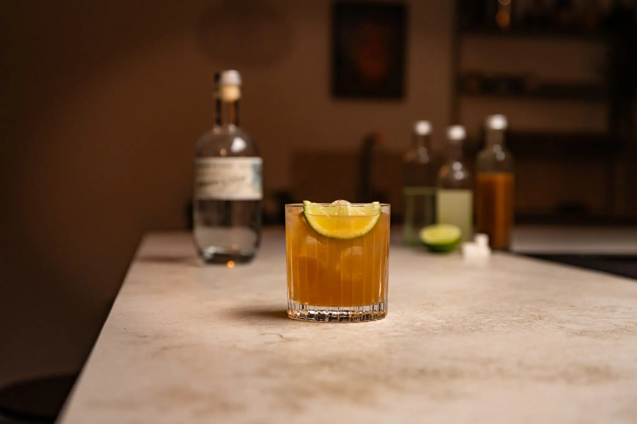 Aguardiente, tamarind paste, lime juice, simple syrup, lime and sugar cubes laid out on a white bar table