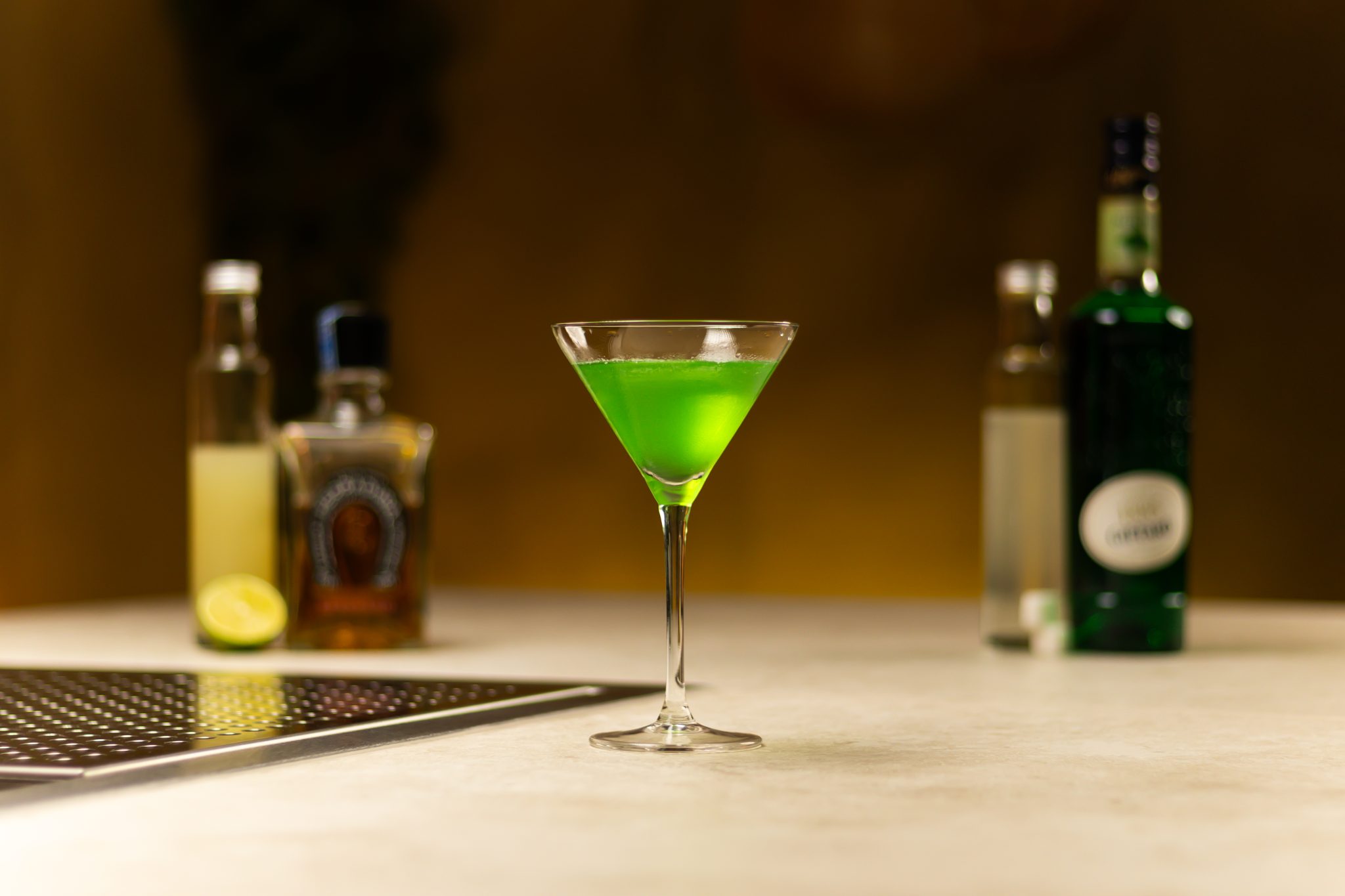 Reposado Tequila, Creme de Menthe, lime juice, rich sugar syrup and lime laid out on a white bar table