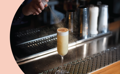 A shot of a bartender dusting a cocktail on a bar table