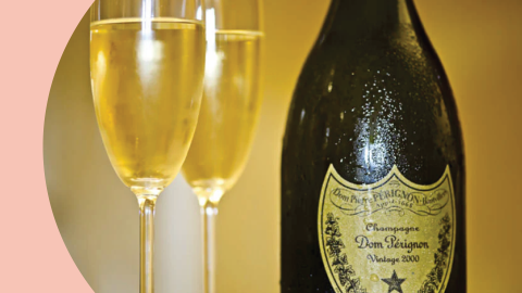 A shot of a Champagne bottle with two champagne flute filled with champagne on the side