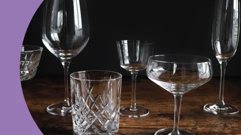 A shot of different types of transparent glassware on a wooden surface and in front of a black background