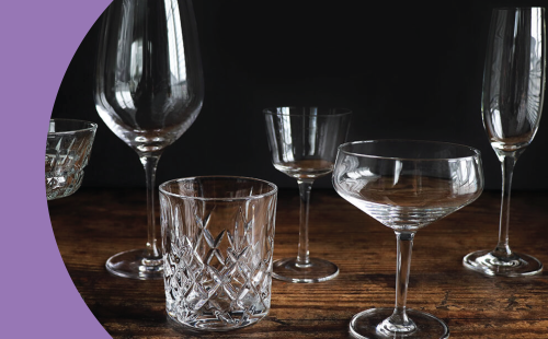 A shot of different types of transparent glassware on a wooden surface and in front of a black background