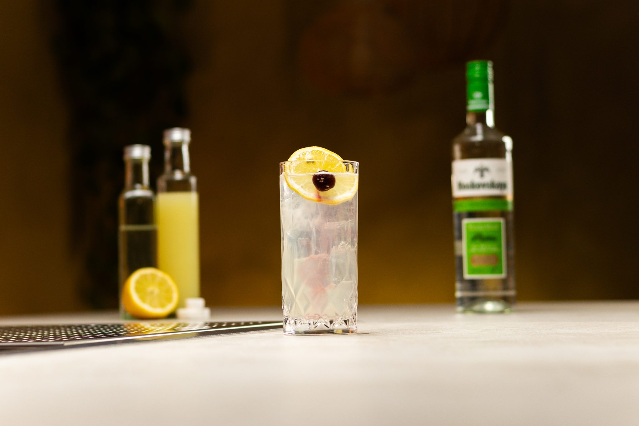 Vodka, lemon juice, sugar cubes, club soda and half lemon laid out on a white bar table