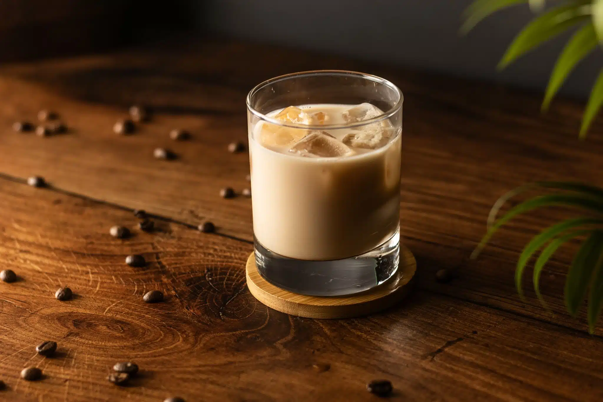A side shot of a White Russian cocktail in an Old Fashioned glass on a wooden background.