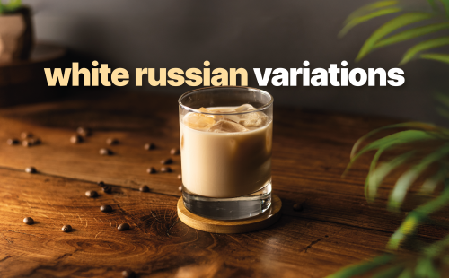 A side shot of a white russian cocktail in an old fashioned glass on a yellow coaster placed on a wooden surface surrounded by coffee beans