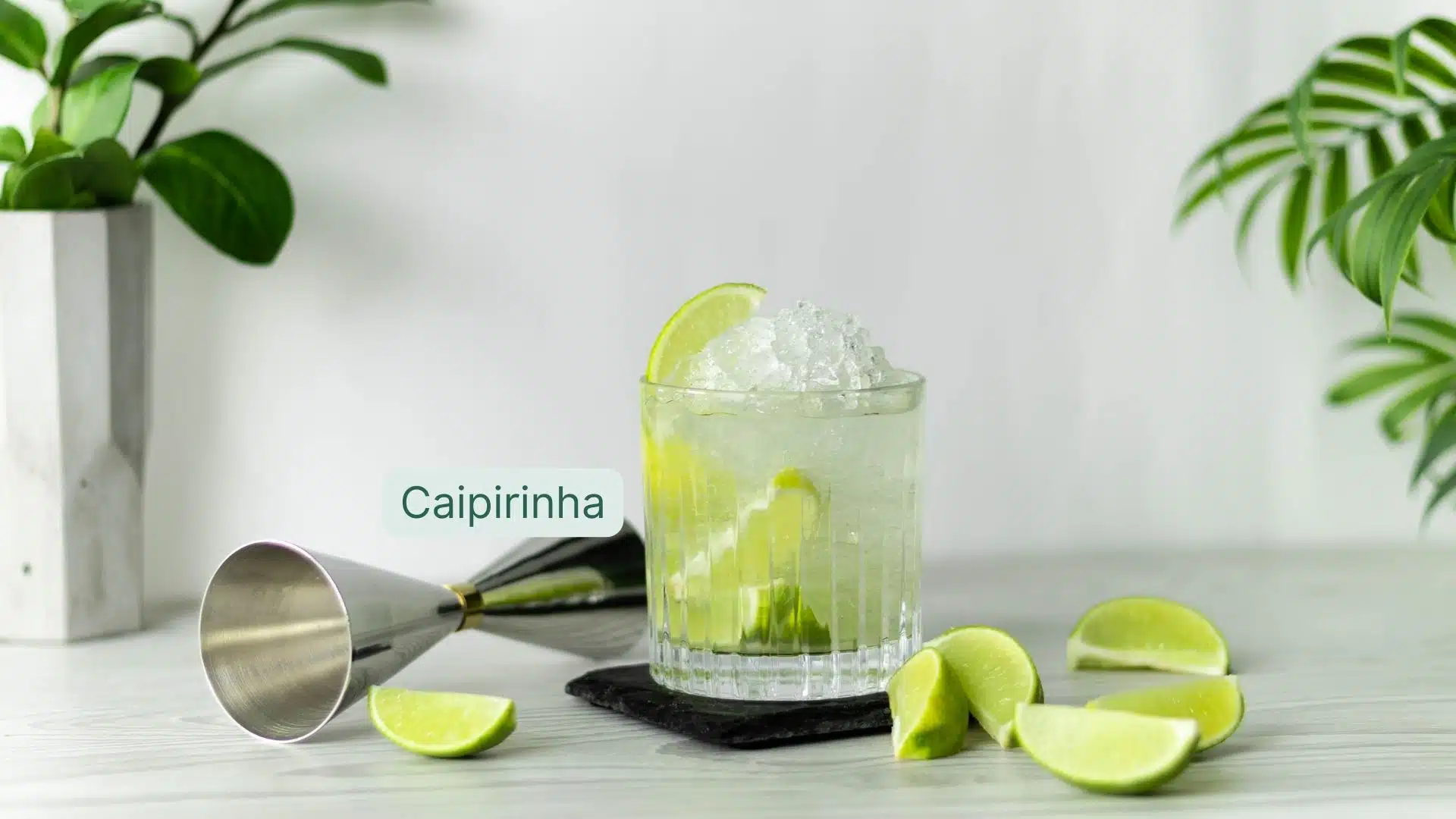 Caipirinha cocktail on black placeholder with fresh lime slices and a jigger around