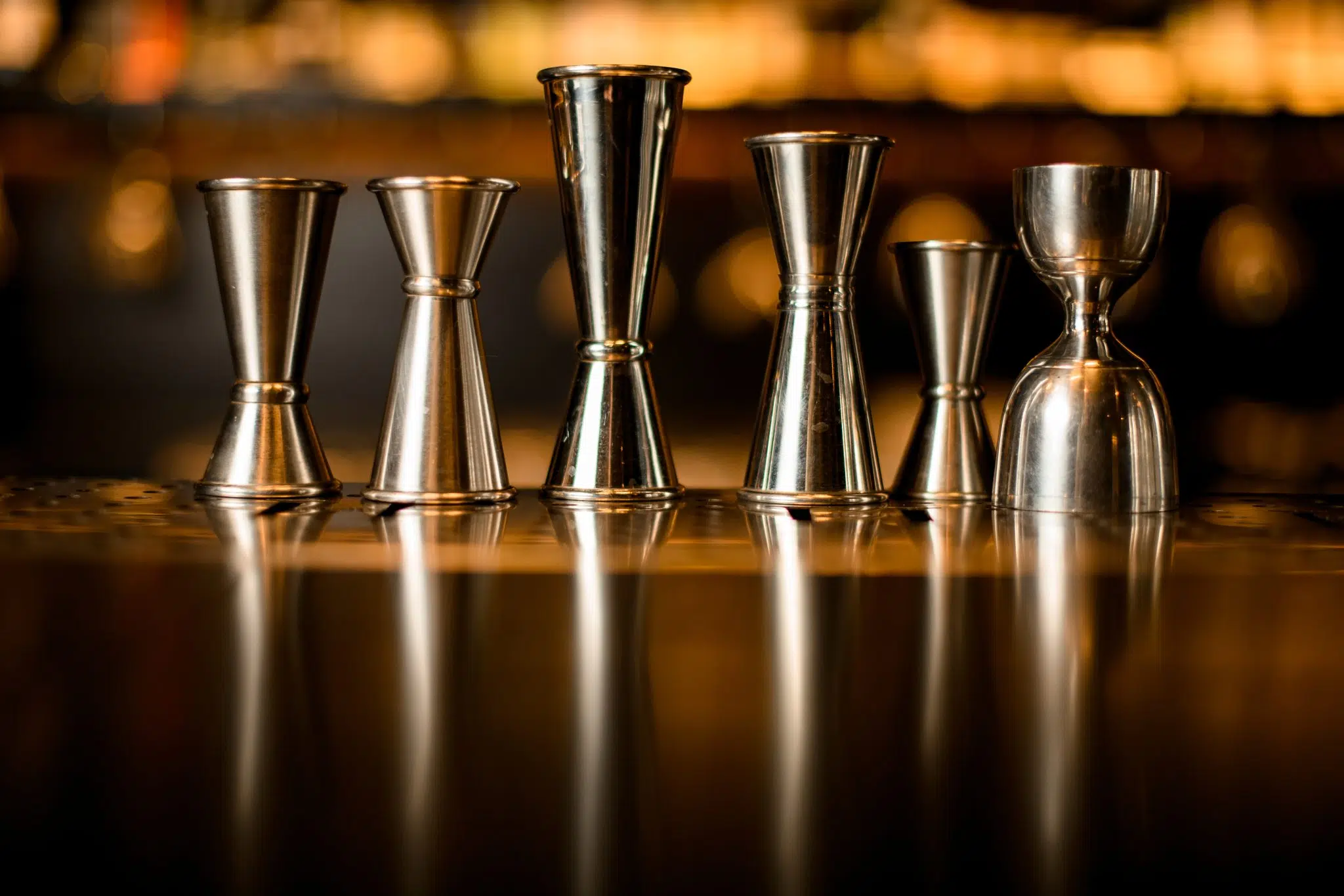 A shot of six different types of jigger on a bar table