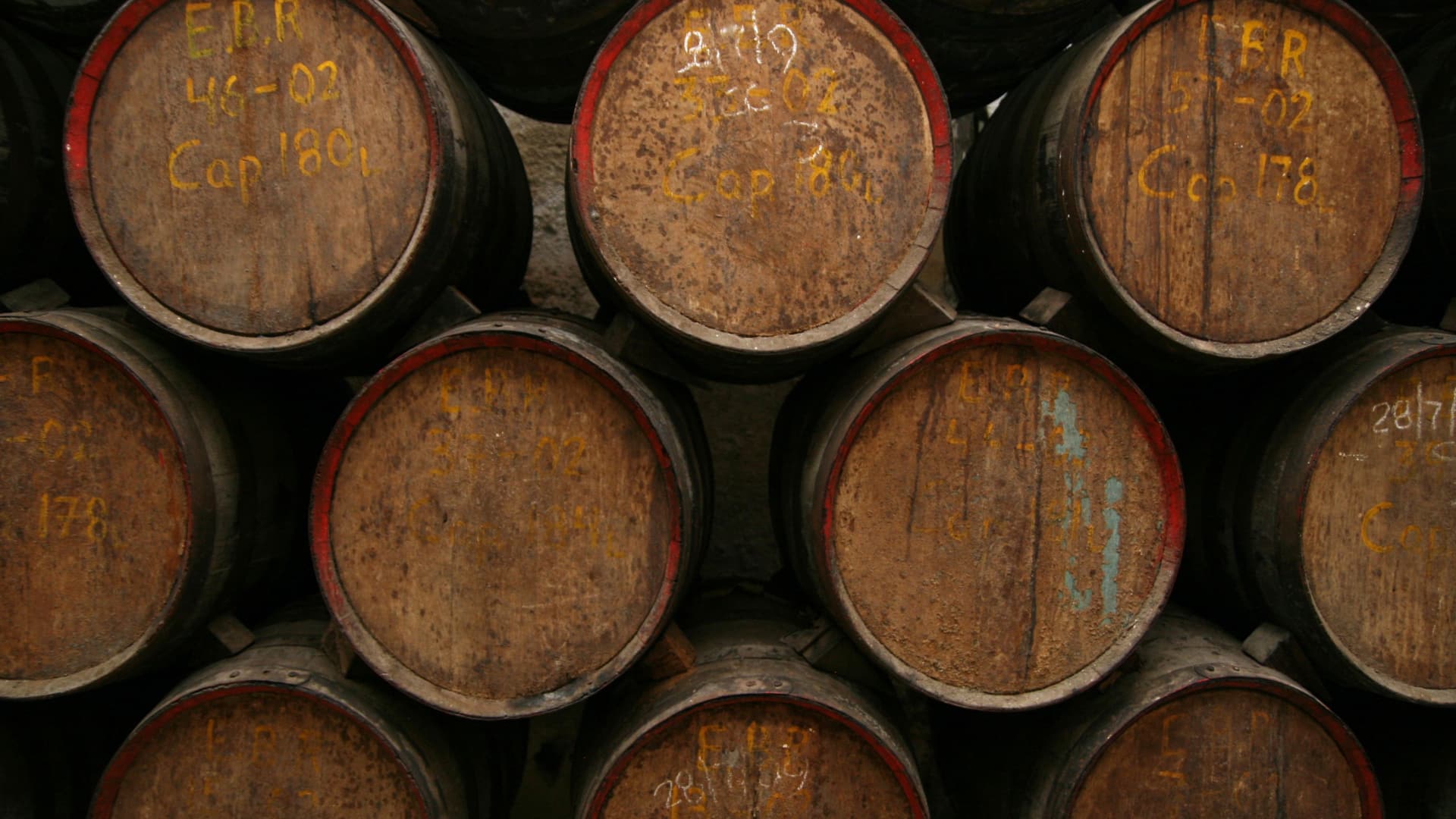 10 stacked rum barrels, some with yellow writing on them