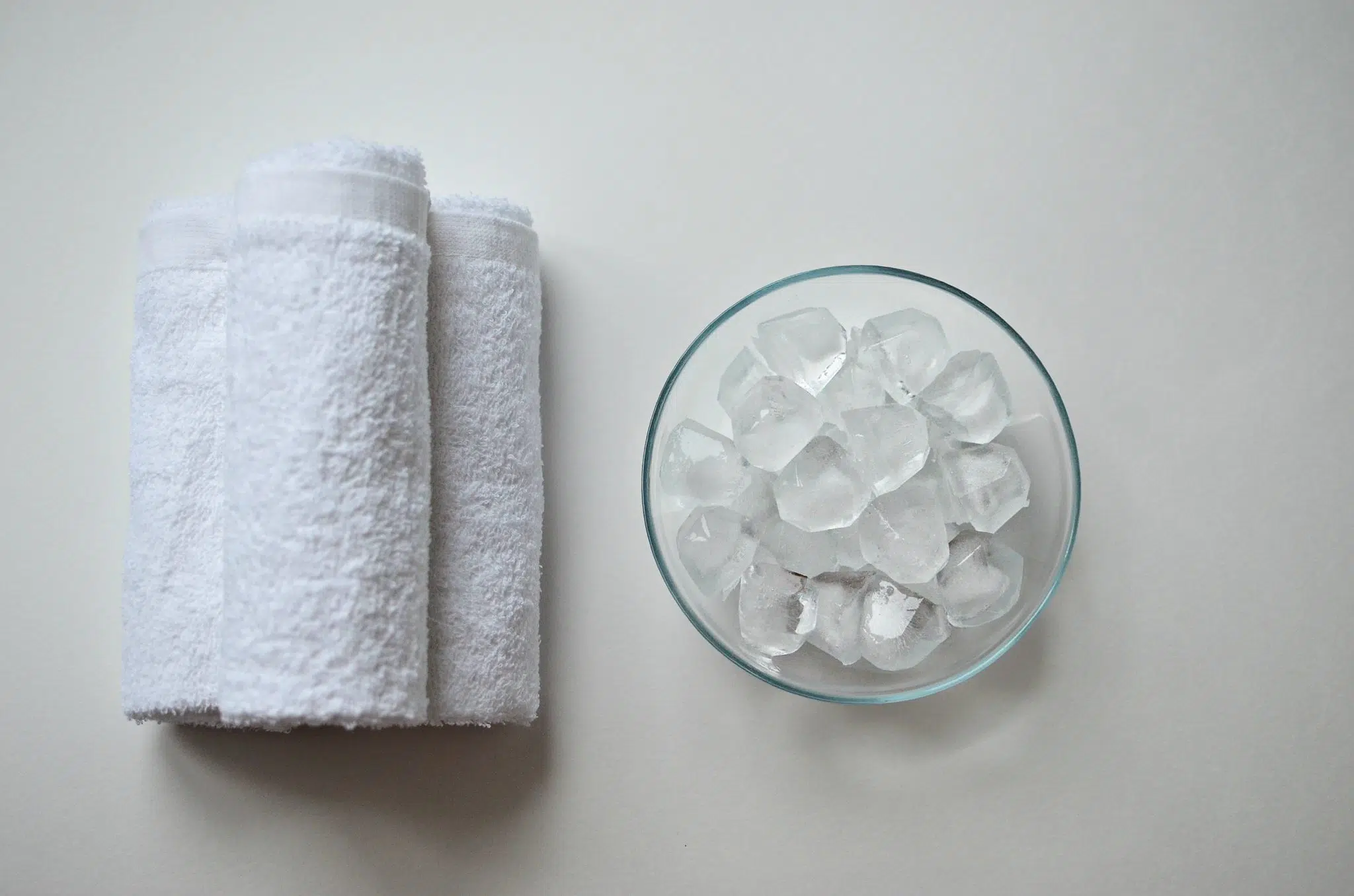 A shot from above with a transparent bowl with ice cubes and three white towels